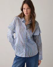 Woman wearing a striped shirt and blue pants against a plain background