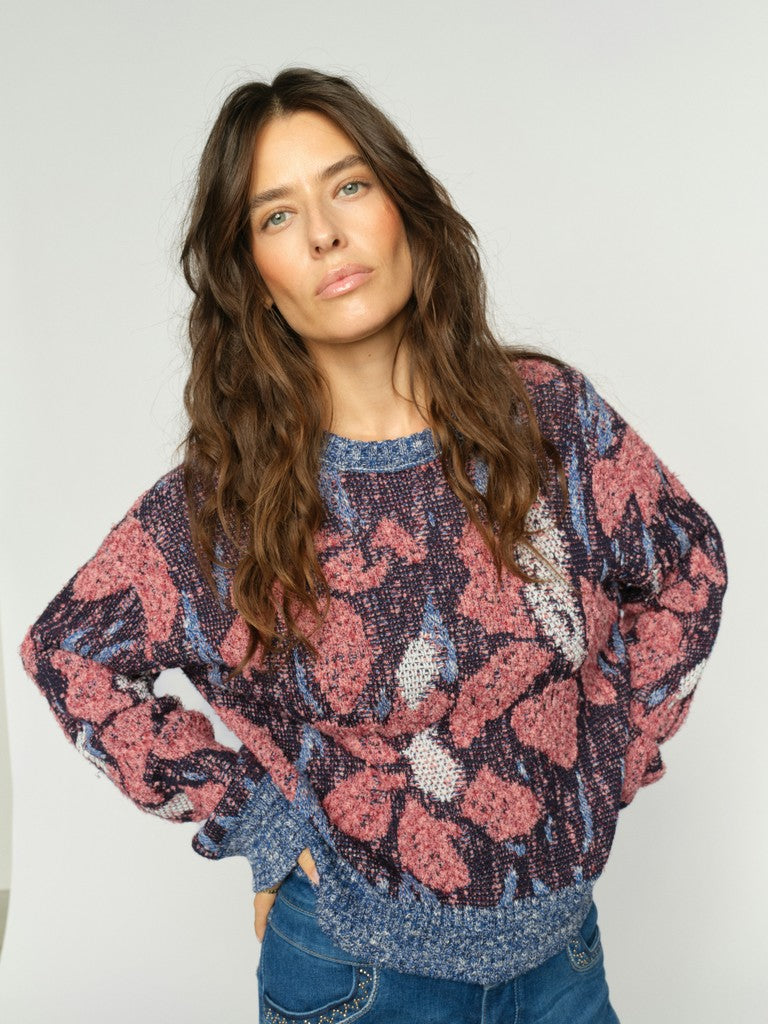 Woman wearing a floral patterned sweater against a plain background