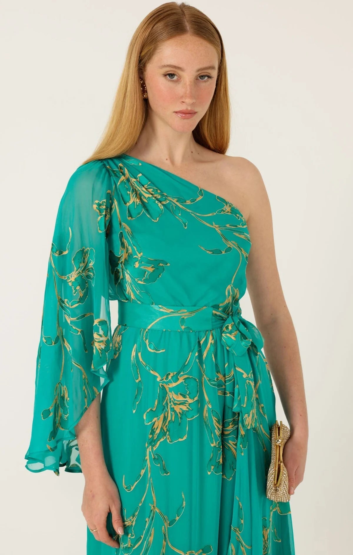 Model wearing one-shoulder neckline and dramatic fluted sleeve Sacha Drake Lorelei Maxi Dress in jade green and gold floral print