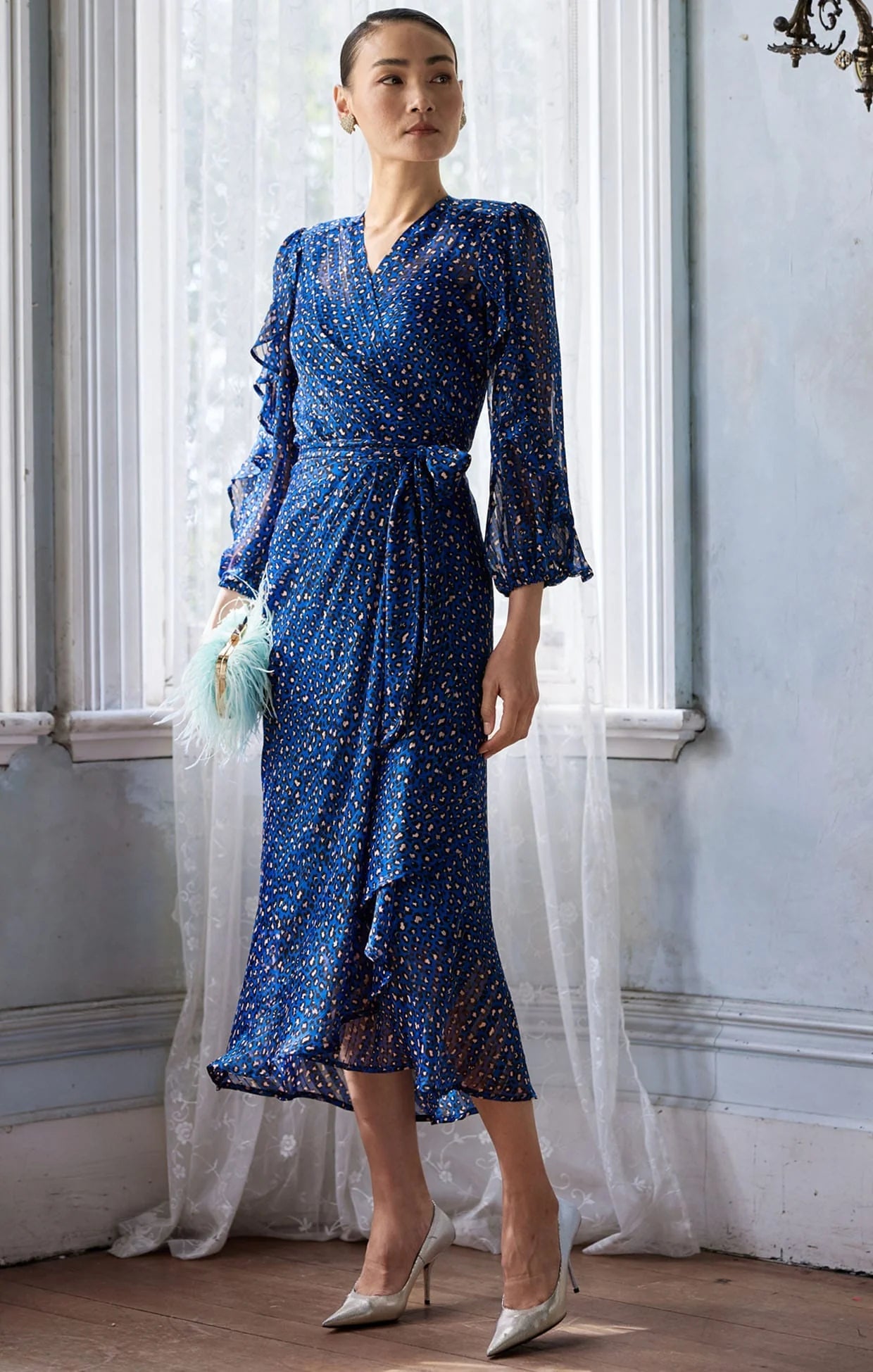 Woman wearing a blue dress with white polka dots in an elegant room.