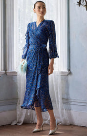 Woman wearing a blue dress with white polka dots in an elegant room.