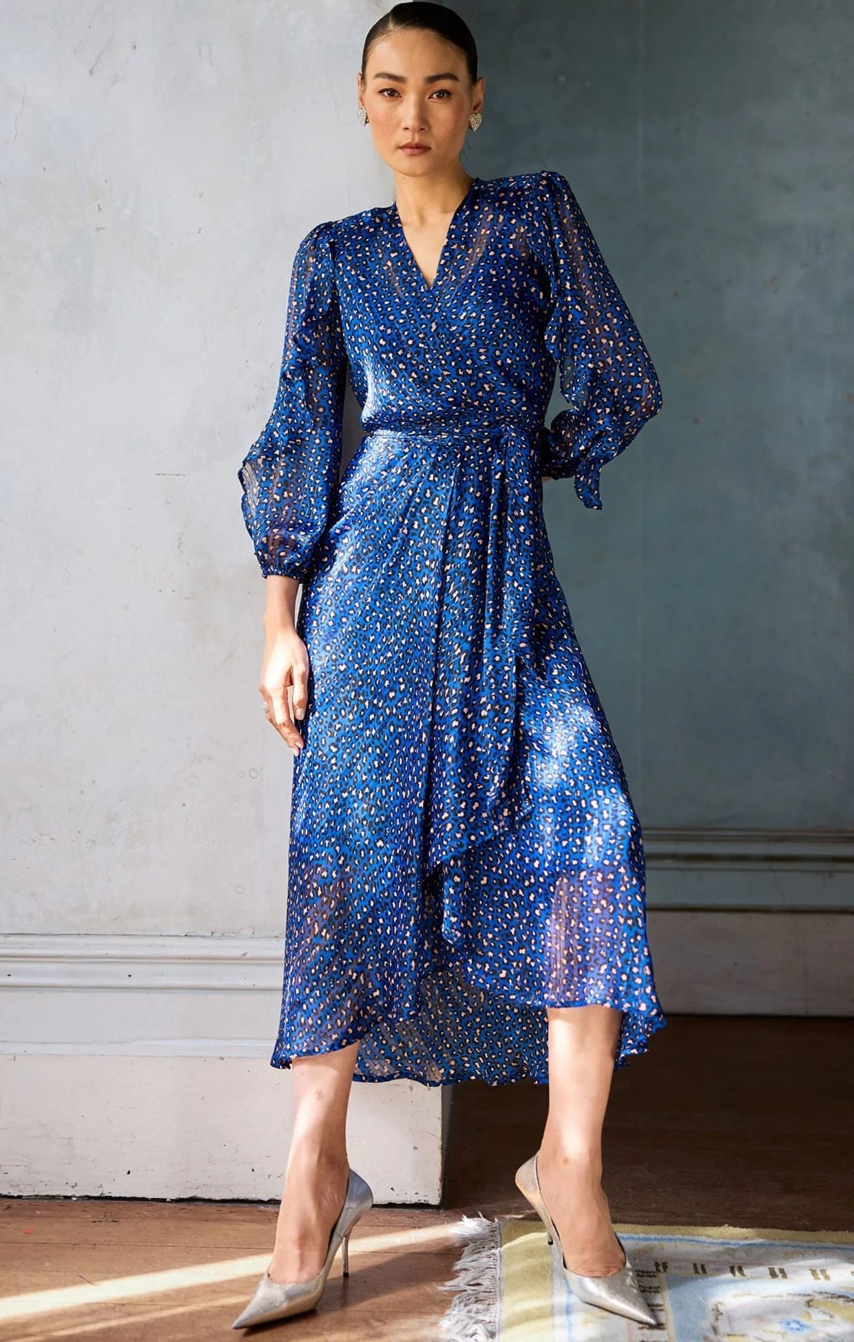 woman in an elegant room wearing Sacha Drake Shona Midi Wrap Dress with black and pink leopard print pattern